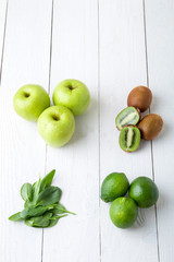 Ingredients for smoothie. Green fruits on white wooden background. Apple, lime, spinach, kiwi. Detox. Healthy food. Top view.