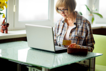 The elderly woman looks in the laptop screen.