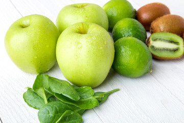 Fototapeta na wymiar Ingredients for smoothie. Green fruits on white wooden background. Apple, lime, spinach, kiwi. Detox. Healthy food.
