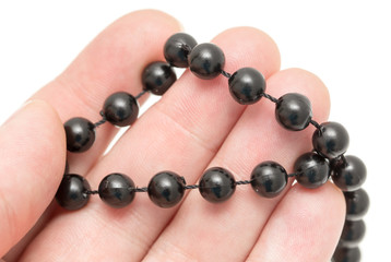 Black beads in hand on a white background