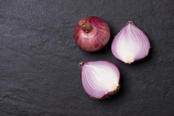 Full and half cut spanish onions on dark background.