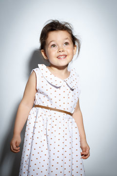 Portrait Of 3 Year Old Little Girl With Dress, Smiling And Posing On Bright White Background