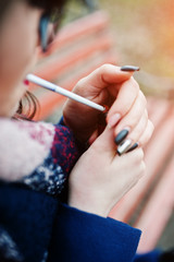 Young girl lighting cigarette outdoors close up. Concept of nicotine addiction by teenagers.