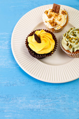 Cupcakes with buttercream. Sweet cake with pistachio nuts cream and small chocolate bar. Dessert with topping. Wooden rustic background.