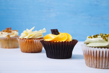 Cupcakes with buttercream. Sweet cake with pistachio cream and small chocolate bar. Dessert on blue wooden background.