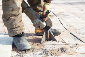 Worker cuts metal in the park