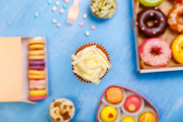 Cupcake with white chocolate, Donuts and Macaroons. Sweet dessert. Cakes with buttercream. Almond macaron cookies. Delivery box.