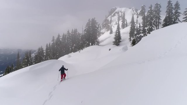 Aerial of Man Snowshoeing to Summit on Mountain Ridge with Fresh Deep Powder