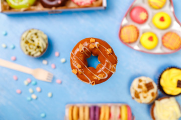 Caramel glazed donut, cupcakes and macaroons. Sweet dessert. Cakes with buttercream. Almond macaron cookies. Delivery box.