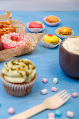 Macaroons, cupcakes and donuts. Mug with whipped cream. Almond macaron cookies with marshmallows. Sweet dessert.