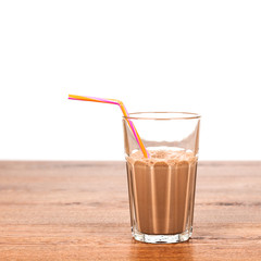 Faceted glass of cold cocoa on a wooden table closeup