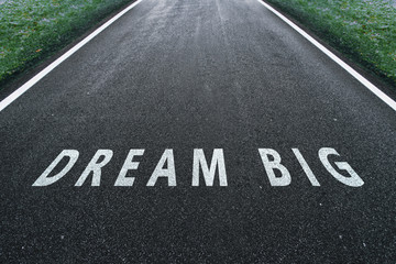 Asphalt road road going straight up with dream big text message. Conceptual business motivation...