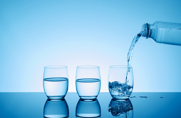 Bottle with creative splashing water in the glass