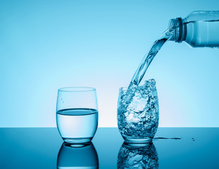 Bottle with creative splashing water in the glass