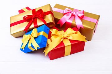 Gift boxes with bow. Colored presents wrapped with paper and ribbons. Christmas or birthday packages. Celebration design. On white table.