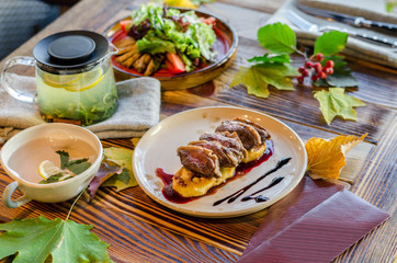 Meat with potatoes and sauce, salad of vegetables and herbs, tea in a cup, kettle and cutlery