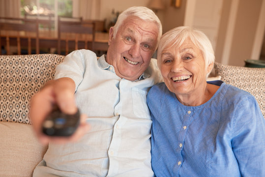 Happy Senior Couple Watching Television Together On Their Sofa