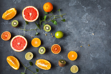 Fruit background. Colorful fresh fruit on dark table. Orange, tangerine, lime, kiwi, grapefruit. Flat lay, top view