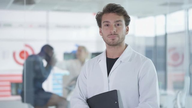  Portrait of sport scientist in white coat, man on exercise bike being tested in background. 