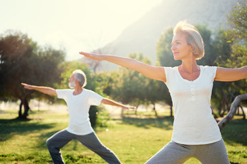 Yoga at park. Senior family couple exercising outdoors. Concept of healthy lifestyle. - obrazy, fototapety, plakaty
