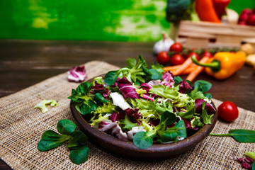 Provence mix salad. Leaves of endive or chicory, lamb and rose salad. Raw vegetables. On wooden table.
