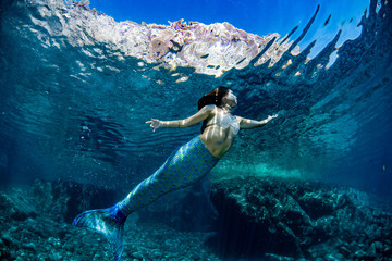 Mermaid swimming underwater in the deep blue sea