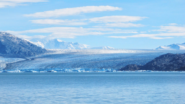 Single blue icebergs and blue sky with white clouds and mountains on the background. Upsala Glacier at Argentino Lake, Los Glaciares National Park, Patagonia, Argentina