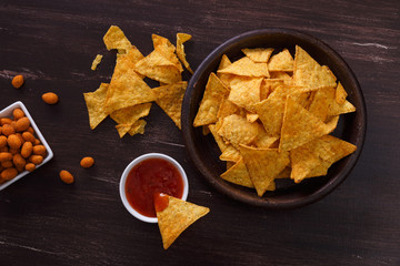 Nachos chips. Tortilla snack with sweet salsa or chilli sauce. Mexican salsa nuts. Rustic plate on wooden background.