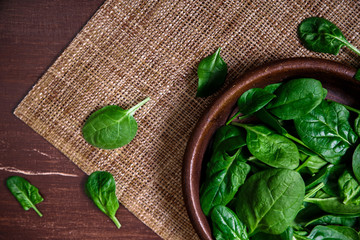 Spinach leaves in bowl. Raw fresh vegetable. Fresh natural plant leaf. Organic bio food on rustic wooden table.
