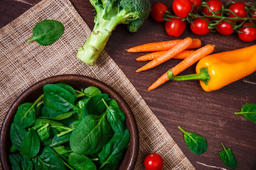Spinach leaves in bowl. Carrot, pepper and cherry tomatoes, brocoli. Raw fresh vegetable. Fresh...