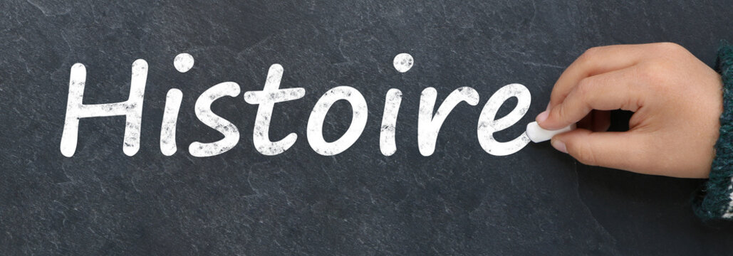 Main d'enfant &eacute;crivant histoire &agrave; la craie sur une ardoise