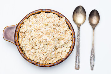 Dry rolled oat flakes oatmeal in a old bowl