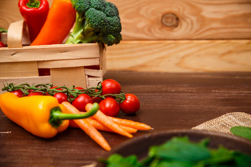 Spinach leaves in bowl. Carrot, pepper and cherry tomatoes. Raw fresh vegetable. Fresh natural plant leaf. Organic food on wooden table.