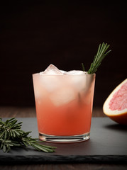 Refreshing grapefruit cocktail with rosemary on dark background. - 143137235