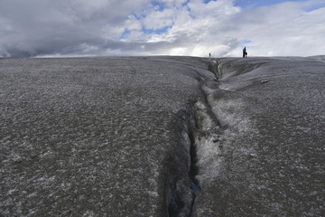 crevasse at a glacier in front of a cloudy sky