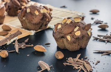 Chocolate muffins with nuts on dark background, selective focus. Chocolate with almond nuts.