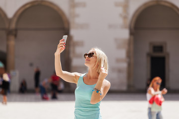 Fototapeta premium Female traveler on the background of Arcades in Wawel Castle in Cracow. Poland. Renaissance. A woman is photographed on her phone against the background of the castle courtyard
