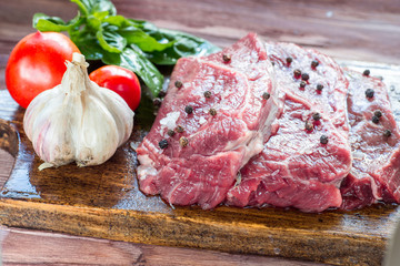 Raw beef steak on a dark wooden table.