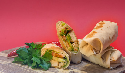 Homemade Chicken Wrap (close-up shot) on vintage chopping board with red background (selective focus).