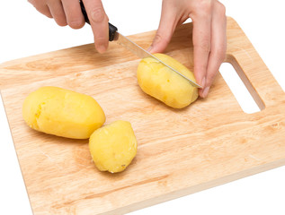 Chef cuts boiled potatoes on board on a white background