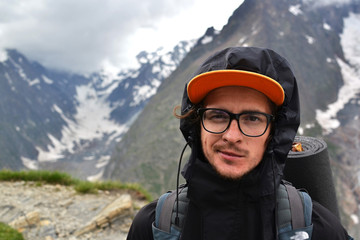 Young guy with glasses traveler, a backpacker traveling through Europe, up into the mountains, the...