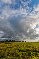 Green autumn fields with country road. Massive stormy clouds. Nature landscape.