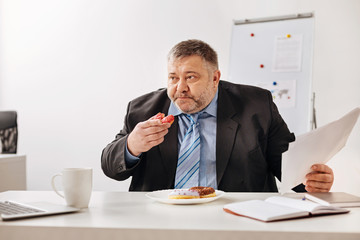 Stressed employee stuffing himself with baked sweets