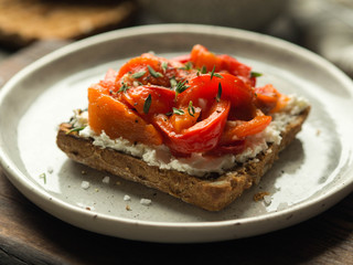 Vegetarian toast with baked pepper and cream cheese on a plate on a wooden board
