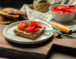 Vegetarian toast with baked pepper and cream cheese on a plate on a wooden board
