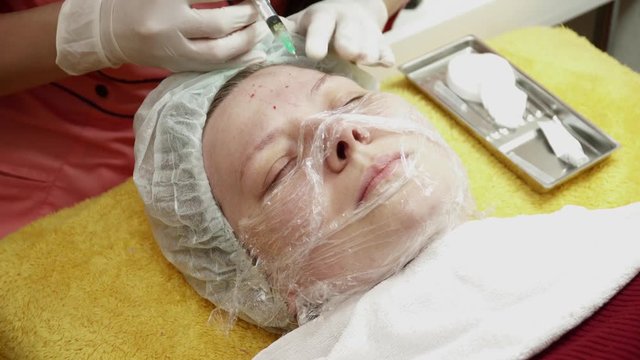 Beautician making injections for the woman in salon