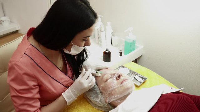 Beautician making injections for the woman in beauty salon