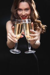Smiling attractive young woman holding two glasses of champagne