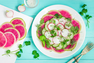 healthy vegan food. watermelon radish, cucumber and radish salad on white plate. top view