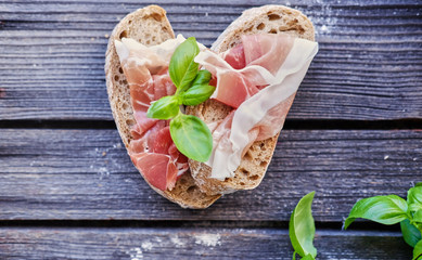 Healthy brown bread with ham, cheese and tomatoes on a wooden table.